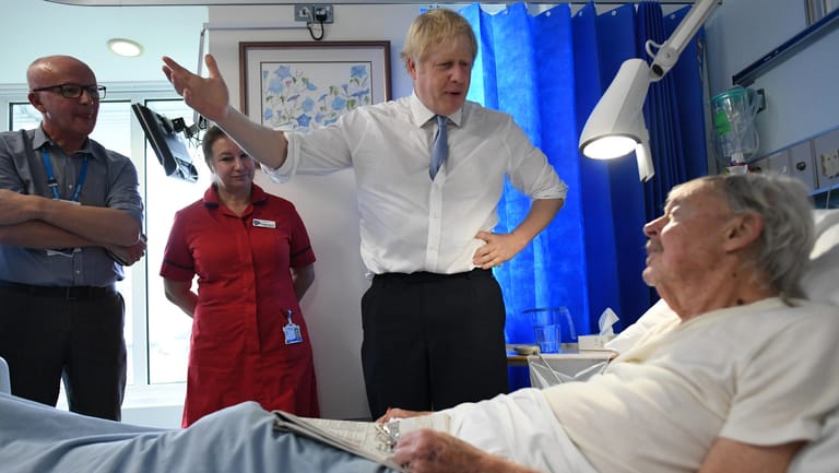 Premierminister Boris Johnson spricht mit einem Patienten im West Cornwall Community Hospital: Nach offiziellen Schätzungen sind in Großbritannien bereits Zehntausende mit dem Coronavirus infiziert.