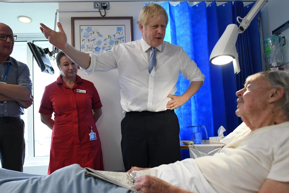 Premierminister Boris Johnson spricht mit einem Patienten im West Cornwall Community Hospital: Nach offiziellen Schätzungen sind in Großbritannien bereits Zehntausende mit dem Coronavirus infiziert.