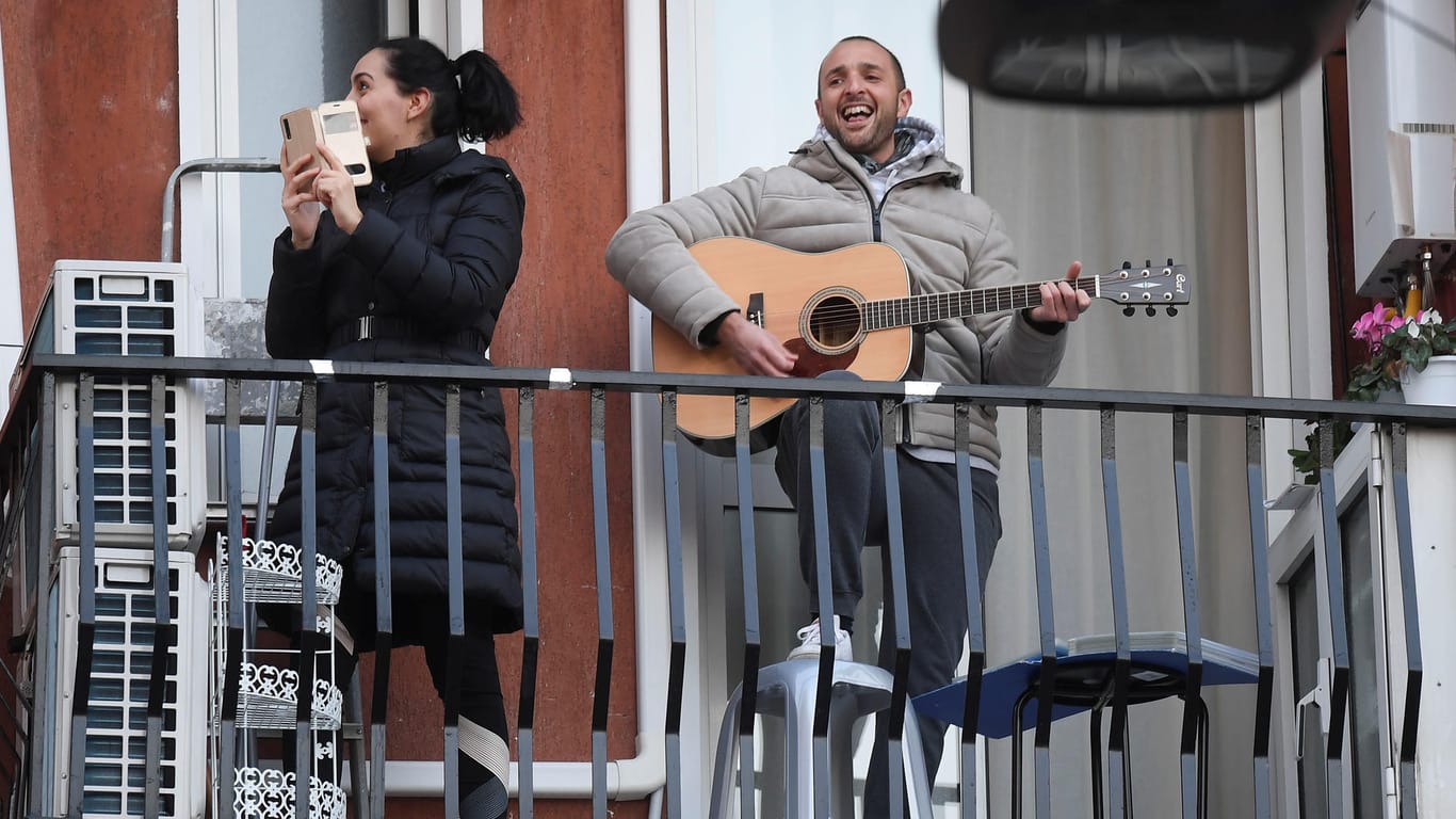 Ein Mann spielt Gitarre auf dem Balkon: Musik bringt Menschen in Zeiten der Corona-Krise zusammen.