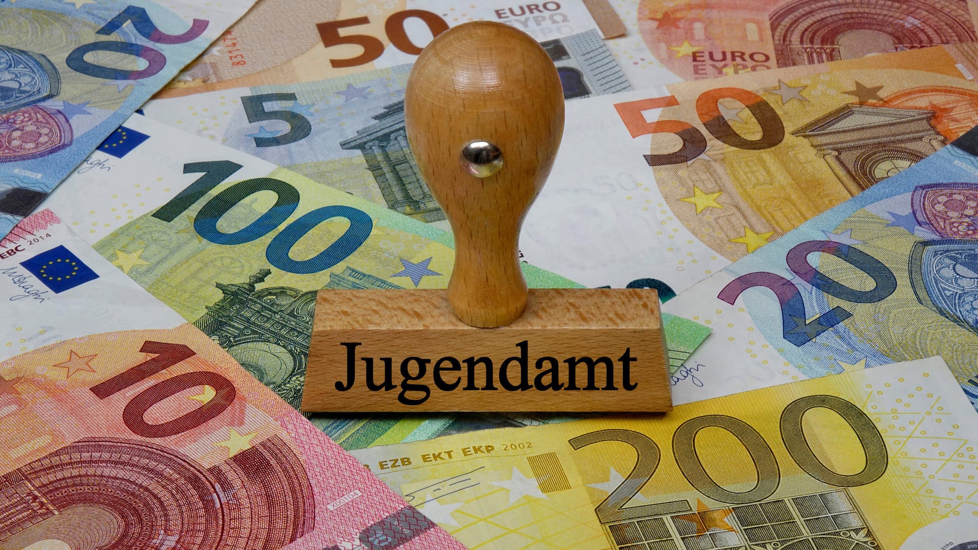Geldscheine und Stempel mit der Aufschrift "Jugendamt": In Düsseldorf sollen Eltern Gebühren, die sie während der Schließzeiten von Kitas und Schulen bezahlt haben, zurückbekommen.