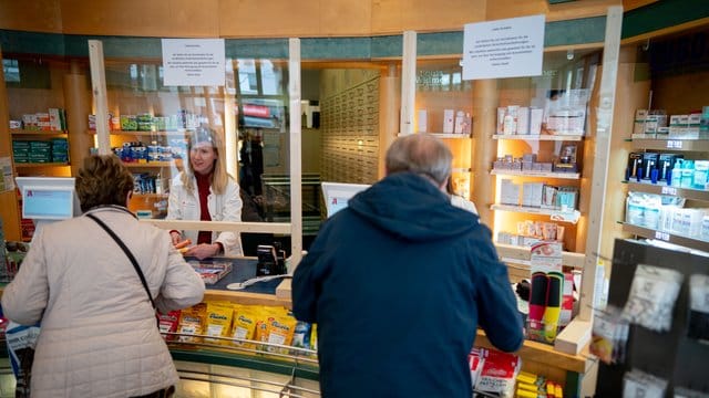 Eine Apothekerin bedient zum Schutz vor dem Coronavirus hinter einer Plexiglasscheibe: Immer mehr Berliner Apotheker wollen sich und die Kunden so schützen.