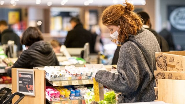 Sicher ist sicher: Mit einer Schutzmaske kauft eine Frau in einem Supermarkt ein. Sicher ist sicher: Mit einer Schutzmaske kauft eine Frau in einem Supermarkt ein.