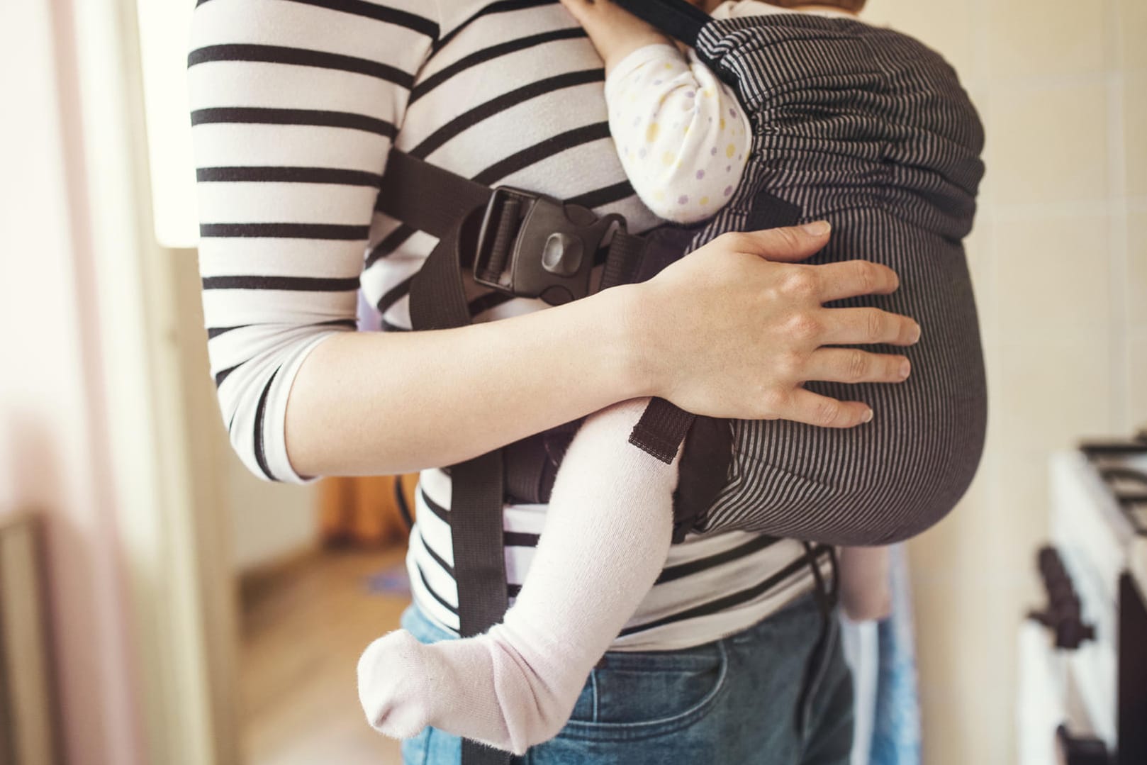 Tragehilfe: Eine Babytrage sollte dem Nachwuchs ermöglichen, in der Anhock-Spreiz-Haltung Platz zu nehmen. Die Beine sind dabei etwas angezogen und leicht nach außen gespreizt.