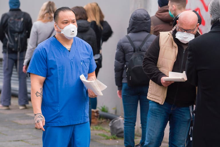 Coranavirus-Tests: Mitarbeiter verteilen Wartenummern an Menschen auf dem Gehweg am Corona-Testcenter des Ärztlichen Bereitschaftsdienstes Hessen.
