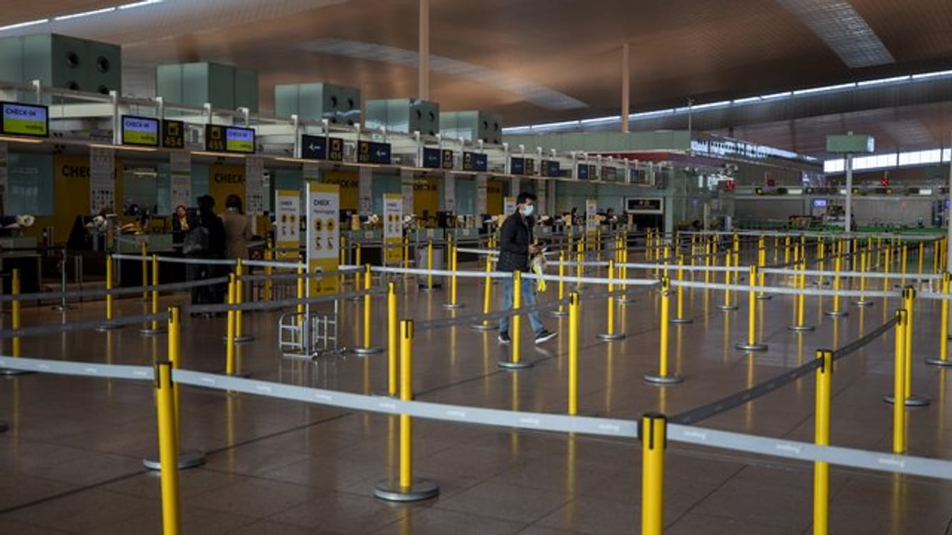Ein Mann mit Mundschutzmaske im leeren Terminal eines Flughafens.