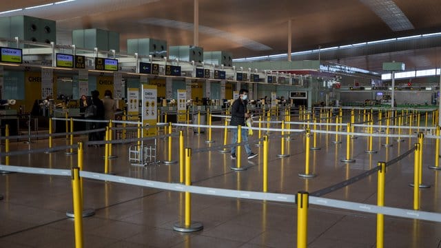 Ein Mann mit Mundschutzmaske im leeren Terminal eines Flughafens. Ein Mann mit Mundschutzmaske im leeren Terminal eines Flughafens.