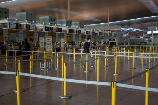 Ein Mann mit Mundschutzmaske im leeren Terminal eines Flughafens.