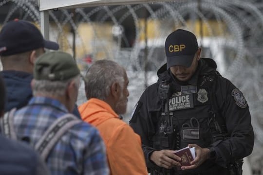 Ein Grenzbeamter kontrolliert in Tijuana am Grenzübergang zwischen Mexiko und den USA einen Pass.