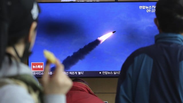 Menschen im Bahnhof von Seoul verfolgen eine Nachrichtensendung, in der über den Abschuss der Raketen berichtet wird. Menschen im Bahnhof von Seoul verfolgen eine Nachrichtensendung, in der über den Abschuss der Raketen berichtet wird.