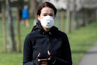 Eine Frau mit Schutzmaske tippt auf ihrem Smartphone: Mit einem Hacktahon will die Bundesrgierung Lösungen im Kampf gegen die Corona-Krise finden.