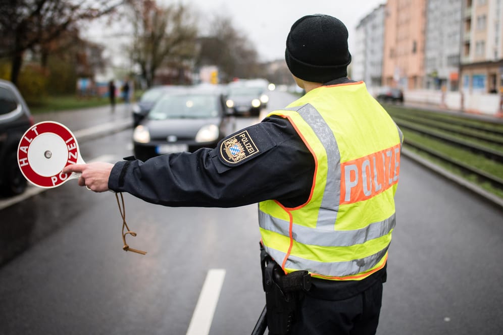 Ein Polizist stoppt an einer Kontrollstelle in München ein Fahrzeug: Bis auf Ausnahmen halten sich die Menschen bislang an die Ausgangsbeschränkungen.