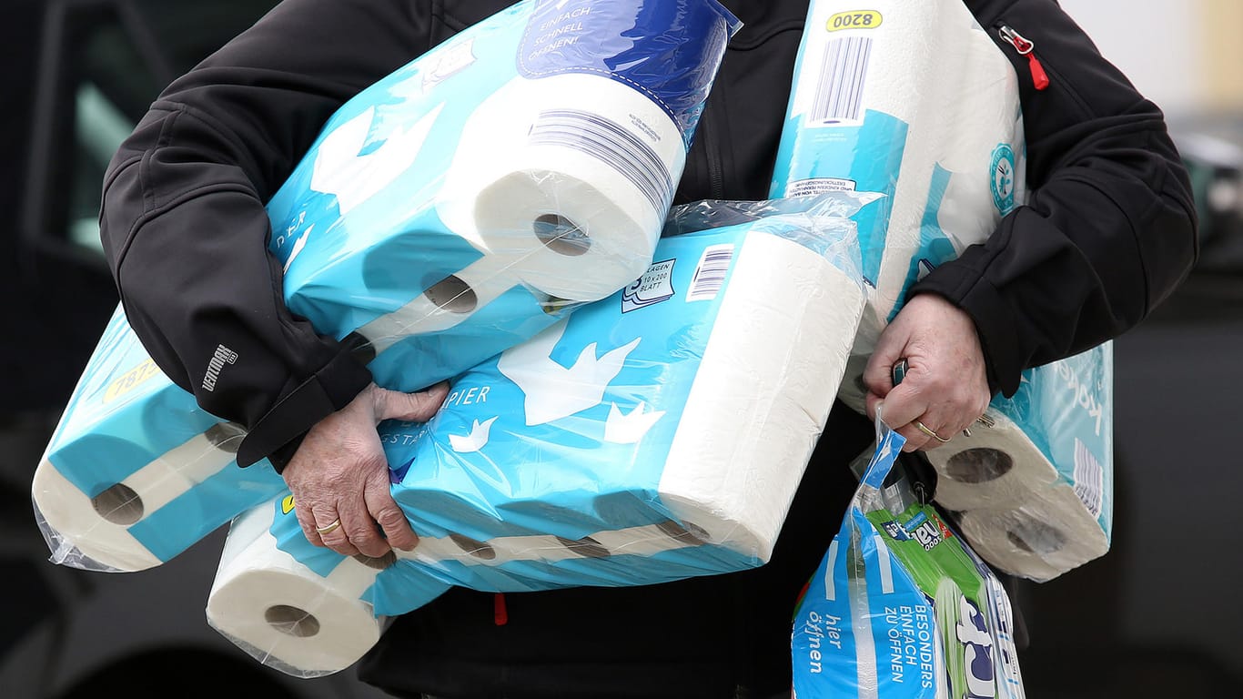 Jemand trägt mehrere Packungen Toilettenpapier: Auf Ebay Kleinanzeigen häufen sich die Wucherangebote.