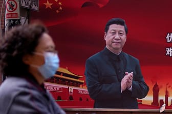 Frau mit Atemmaske vor einem Porträt des chinesischen Staatspräsidenten Xi Jinping: Kritik an der Corona-Strategie der staatlichen Führung führt rasch zur Einstufung als Dissident.