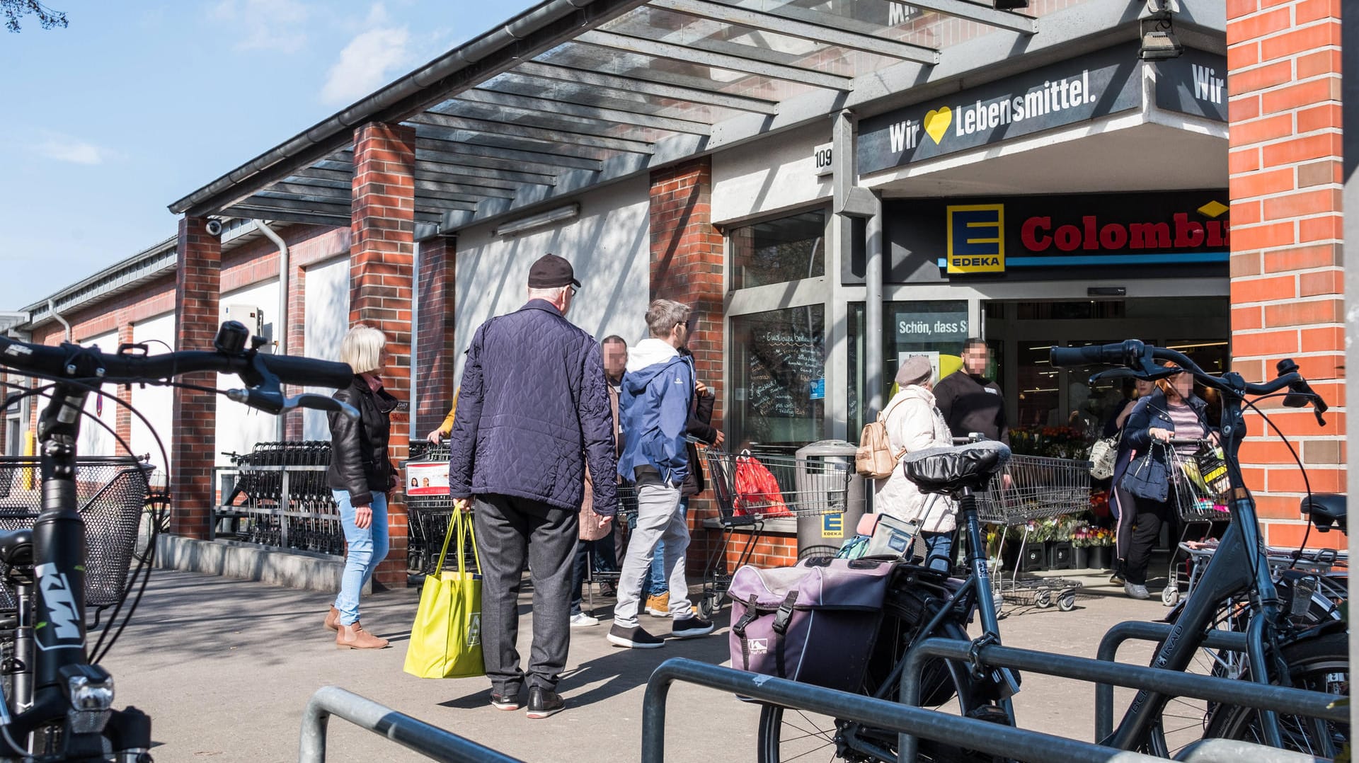 Ein Security-Mitarbeiter regelt Kundeneinlass vor dem Eingang einer Edeka-Filiale in Berlin Zehlendorf.