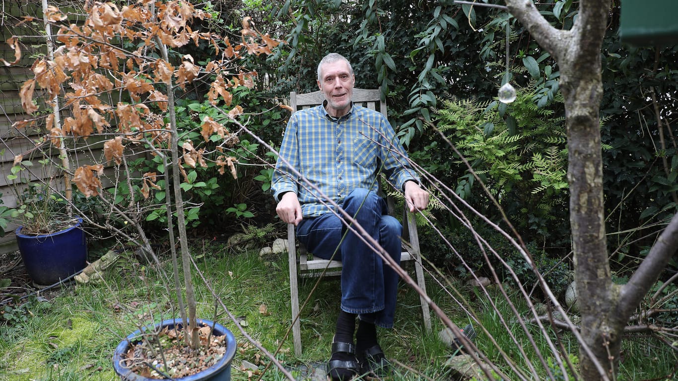Andrew Davies, Filmemacher und Kunsthistoriker sitzt in seinem Garten.