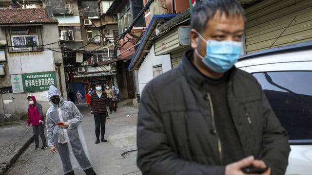 Menschen halten Abstand, während sie in Wuhan für Schweinefleisch anstehen. Menschen halten Abstand, während sie in Wuhan für Schweinefleisch anstehen.
