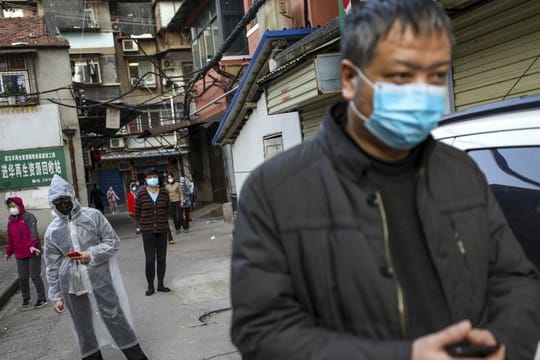 Menschen halten Abstand, während sie in Wuhan für Schweinefleisch anstehen.