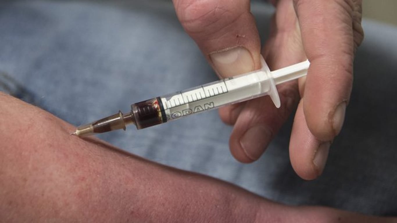 Ein Drogensüchtiger spritzt sich in einem Druckraum einen Schuss Heroin in den Unterarm.