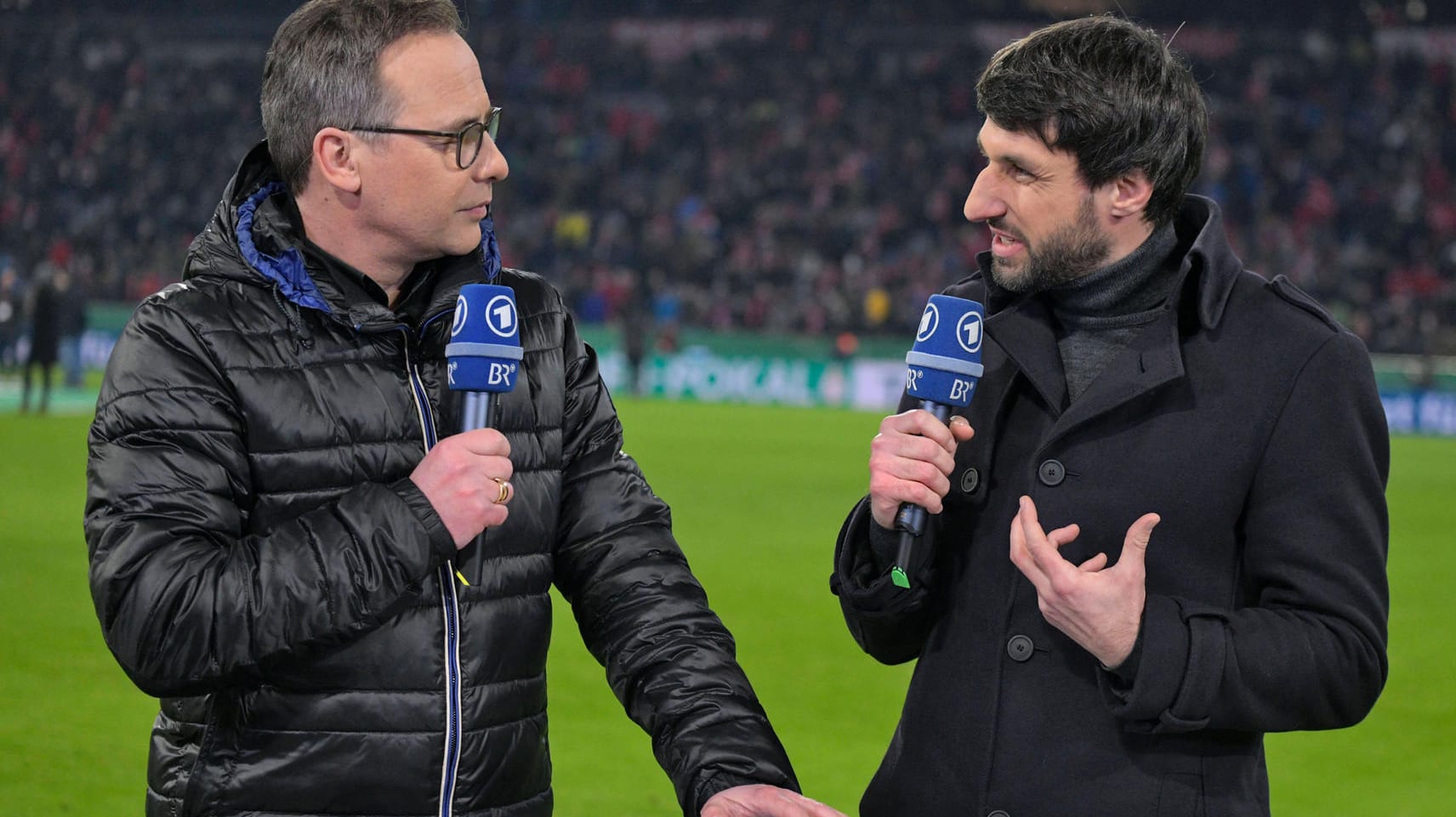 ARD-Moderator Matthias Opdenhövel (li) und Experte Thomas Broich diskutieren am Spielfeldrand.