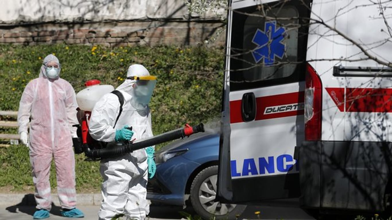 Ein Mann, der Schutzkleidung trägt, desinfiziert in Belgrad einen Krankenwagen.