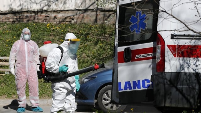 Ein Mann, der Schutzkleidung trägt, desinfiziert in Belgrad einen Krankenwagen. Ein Mann, der Schutzkleidung trägt, desinfiziert in Belgrad einen Krankenwagen.