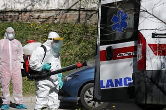 Ein Mann, der Schutzkleidung trägt, desinfiziert in Belgrad einen Krankenwagen.