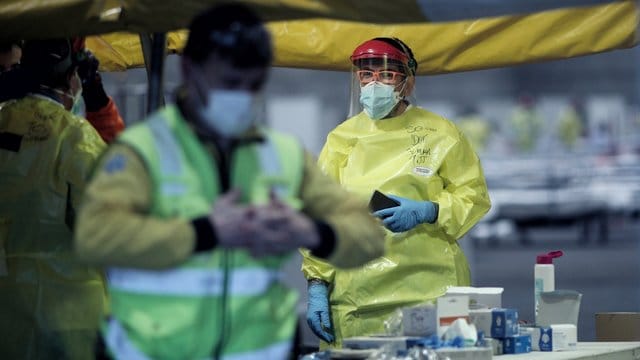 Gesundheitspersonal mit Schutzkleidung auf dem Gelände der Madrider Messe, wo Patienten mit leichten Symptomen behandelt werden. Gesundheitspersonal mit Schutzkleidung auf dem Gelände der Madrider Messe, wo Patienten mit leichten Symptomen behandelt werden.