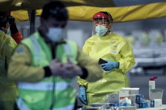 Gesundheitspersonal mit Schutzkleidung auf dem Gelände der Madrider Messe, wo Patienten mit leichten Symptomen behandelt werden.
