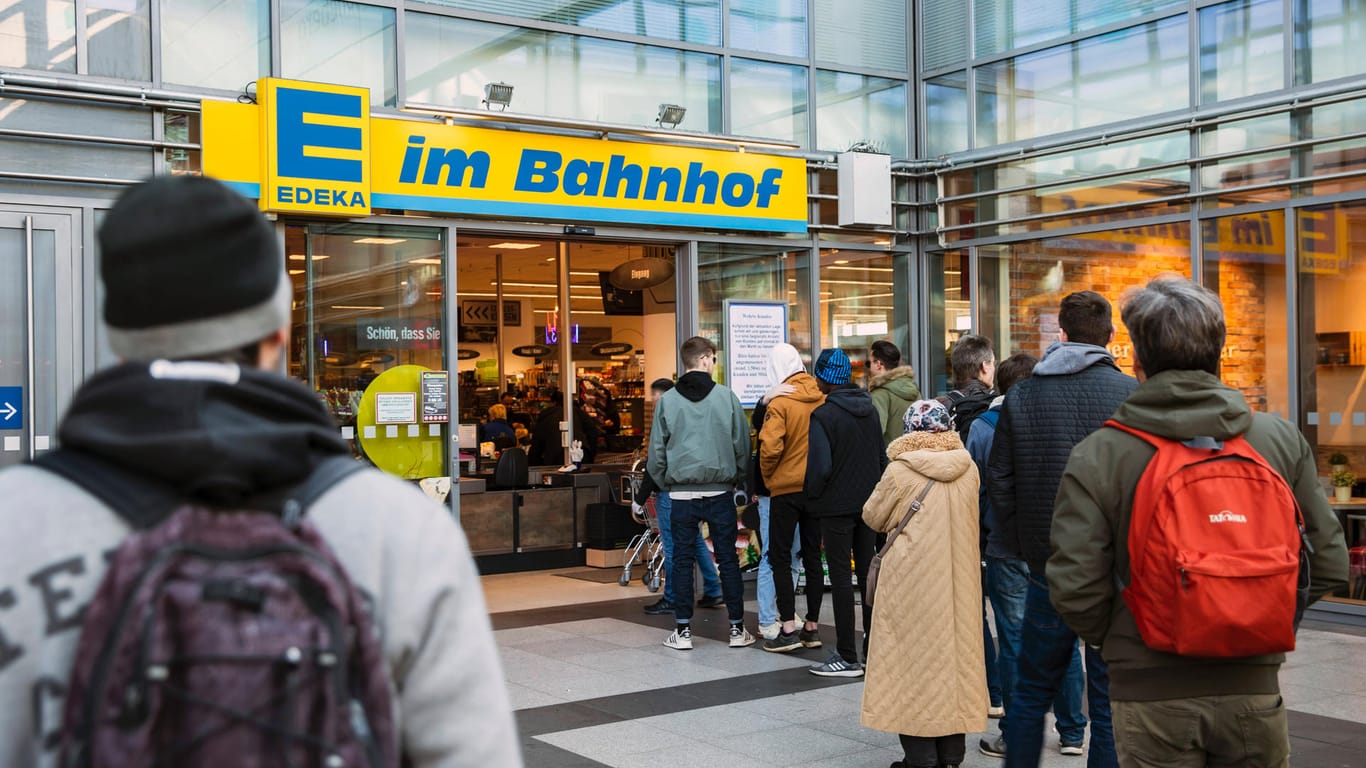 Menschen stehen Schlange vor einem Edeka in Berlin: Trotzdem reagieren viele Supermärkte mit verkürzten Öffnungszeiten.
