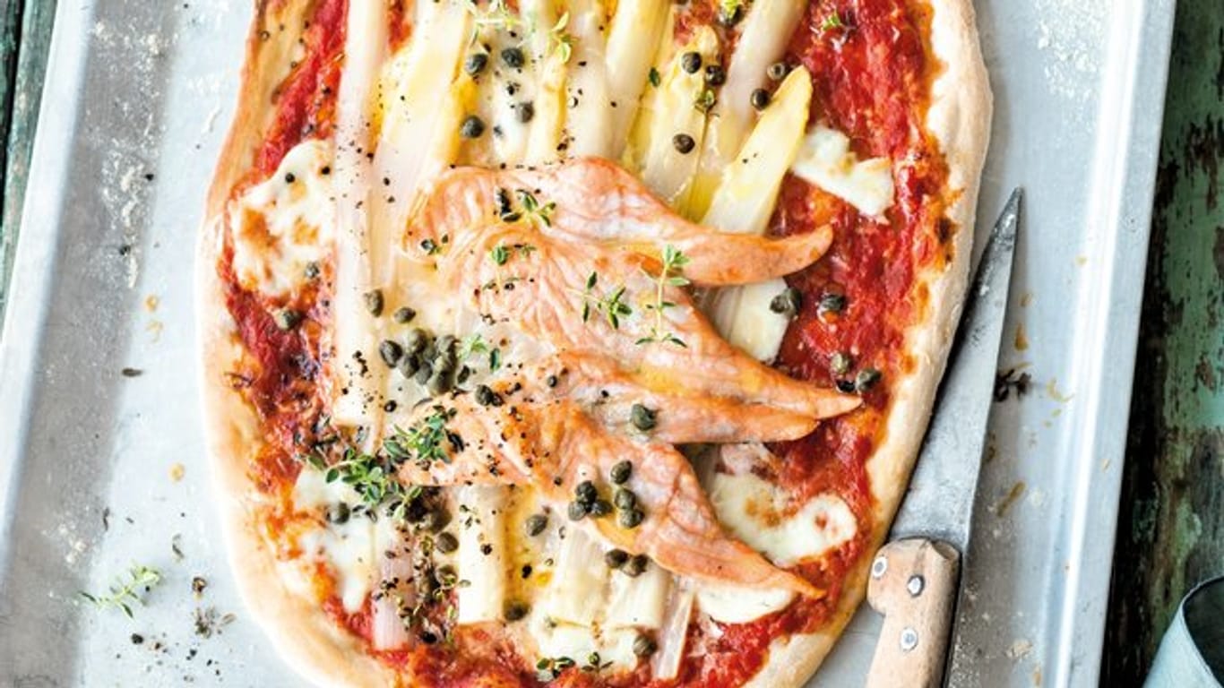 Auf den fertigen Pizzateig kommen Tomatensugo, Parmesan, Mozzarella, Lachs, Spargel, Kapern und Zitronenthymian.