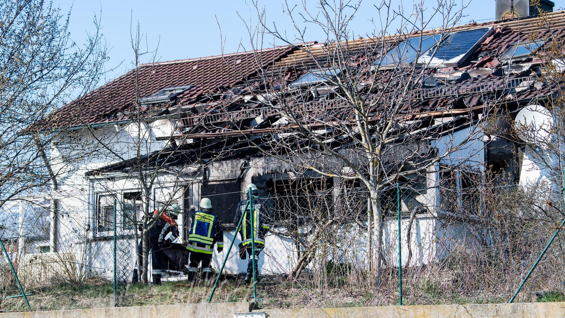 Feuerwehrmänner stehen vor einem ausgebrannten Einfamilienhaus in Bodenkirchen: Zwei Menschen sind bei dem Brand in Niederbayern ums Leben gekommen.