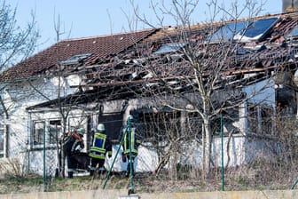 Feuerwehrmänner stehen vor einem ausgebrannten Einfamilienhaus in Bodenkirchen: Zwei Menschen sind bei dem Brand in Niederbayern ums Leben gekommen.