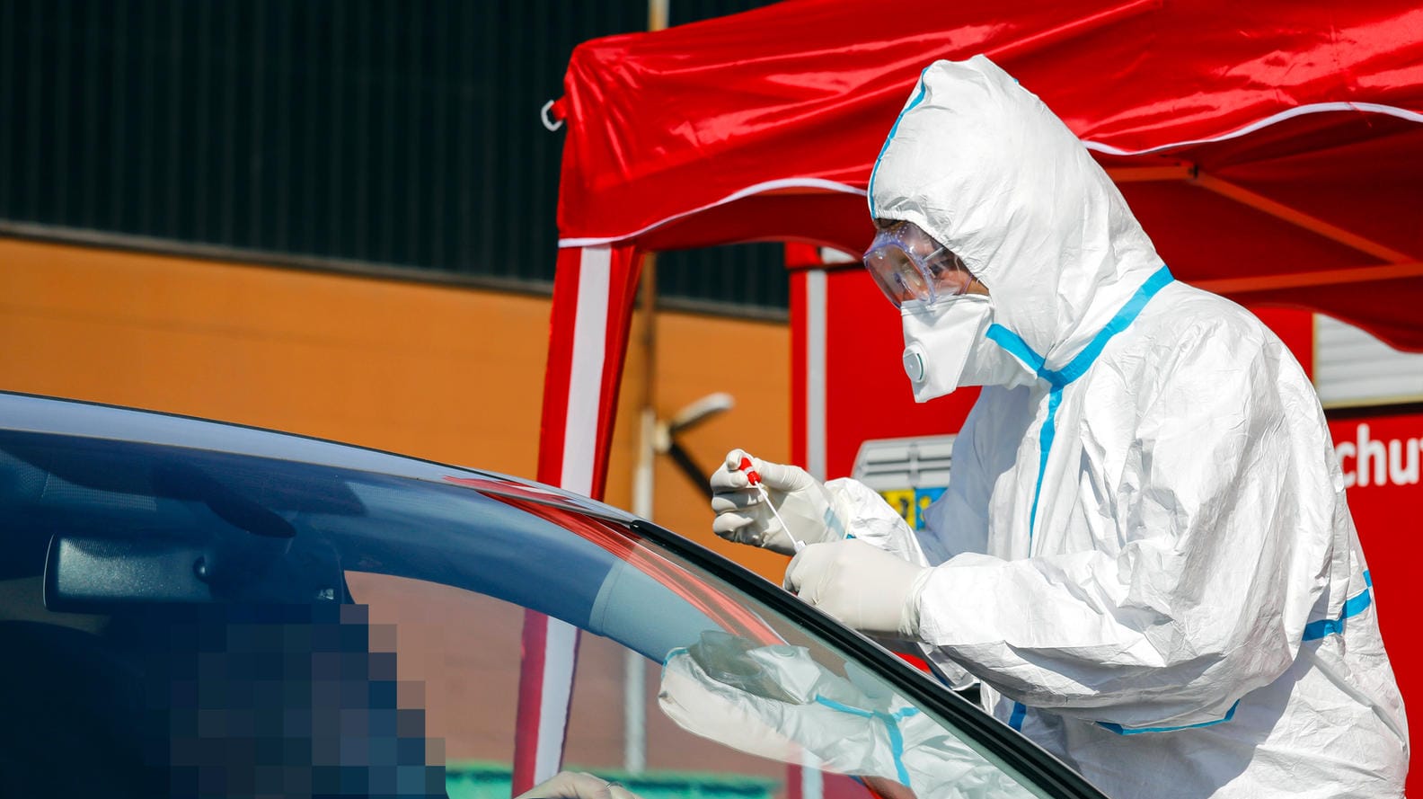 An einer mobilen Teststation entnimmt ein Arzt einen Abstrich durch das Autofenster: In Rheinland-Pfalz wurden die Abstriche auf einem Parkplatz genommen - mit überraschendem Ergebnis. (Symbolbld)