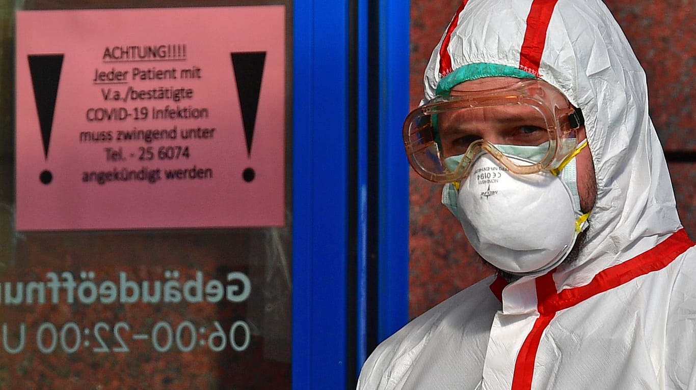 Krankenhaus in Leipzig: Ein Mann in Schutzkleidung öffnet Covid-19-Patienten eine Tür für den Krankentransport.