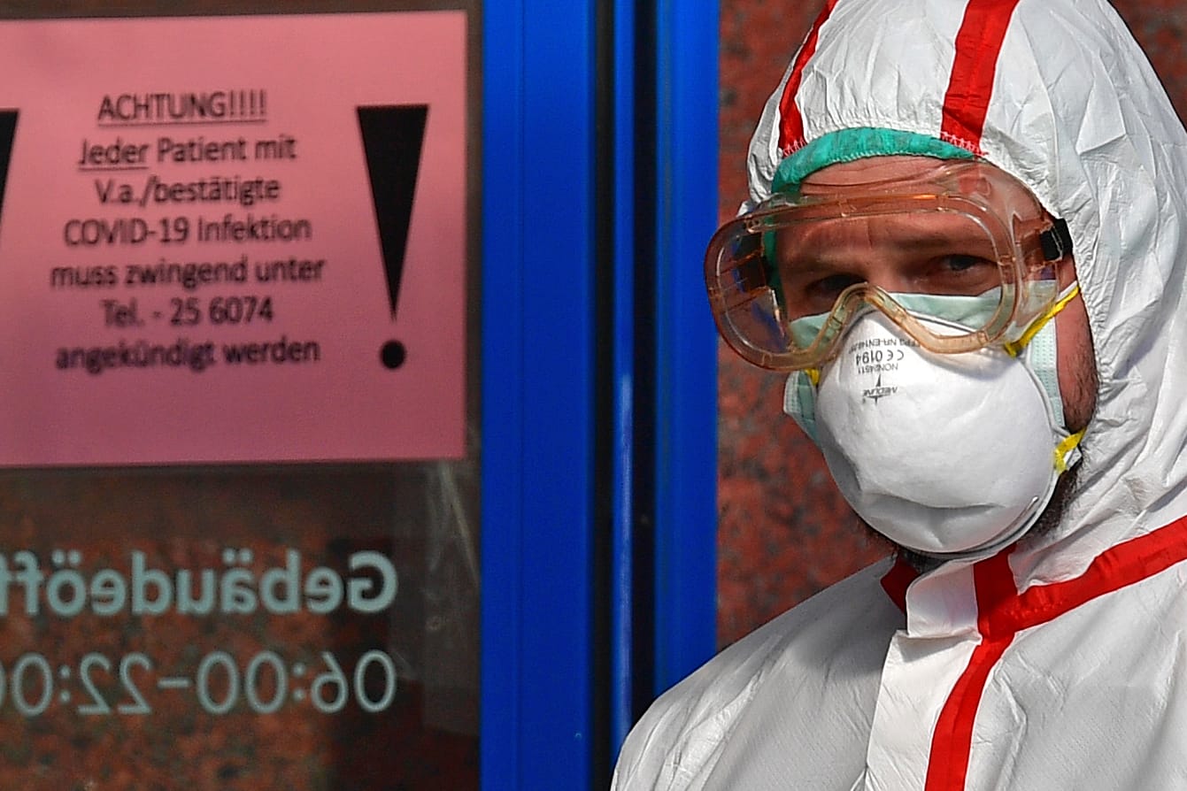 Krankenhaus in Leipzig: Ein Mann in Schutzkleidung öffnet Covid-19-Patienten eine Tür für den Krankentransport.