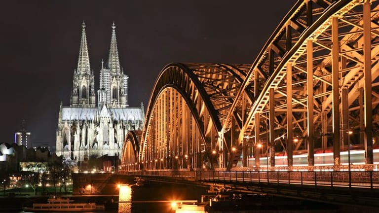 Der Dom in Köln und die Hohenzollernbrücke sind erleuchtet.
