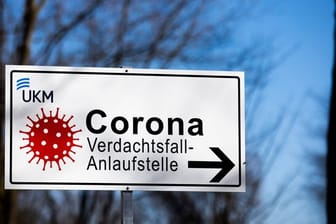 Ein Hinweisschild mit der Aufschrift "Corona Verdachtsfall-Anlaufstelle" steht vor der Uniklinik Münster.