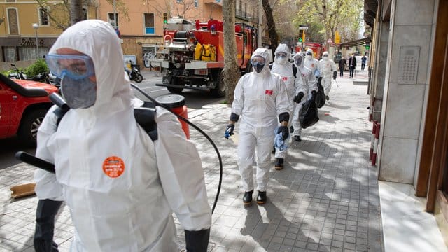 Soldaten in Schutzanzügen in Barcelona sind mit Abstand in Richtung eines Seniorenheims für Desinfektionsarbeiten unterwegs.