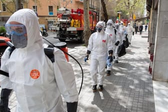 Soldaten in Schutzanzügen in Barcelona sind mit Abstand in Richtung eines Seniorenheims für Desinfektionsarbeiten unterwegs.