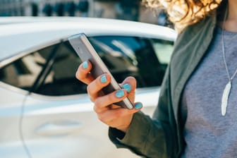 Eine Frau mit einem Smartphone: Einer Untersuchung zufolge hinkt Deutschland in der Mobilfunkversorgung in der DACH-Region hinterher.