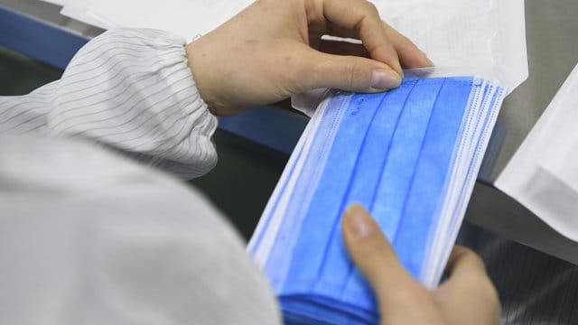 Ein Mitarbeiter eines Herstellers medizinischer Geräte verpackt in einer Produktionswerkstatt Mundschutz-Masken. Ein Mitarbeiter eines Herstellers medizinischer Geräte verpackt in einer Produktionswerkstatt Mundschutz-Masken.