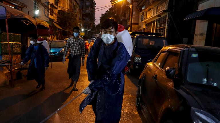 In Myanmar versprüht ein Mann auf der Straße Desinfektionsmittel: Die Corona-Krise hat die ganze Welt erreicht.