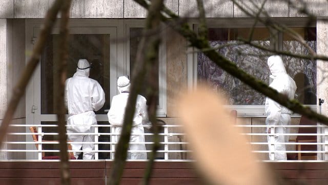 Pflegekräfte in Schutzkleidung vor einem Altenheim.