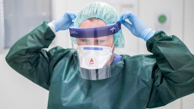 Die Stationsleiterin einer Infektionsstation beim Anlegen ihrer Schutzkleidung. Die Stationsleiterin einer Infektionsstation beim Anlegen ihrer Schutzkleidung.