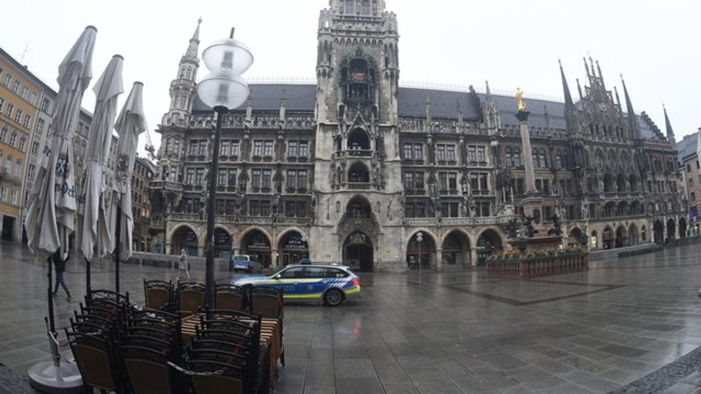 Vor dem Müncher Rathaus fährt ein Polizeiauto über den leeren Marienplatz.