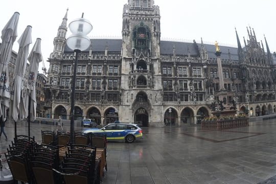 Vor dem Müncher Rathaus fährt ein Polizeiauto über den leeren Marienplatz.