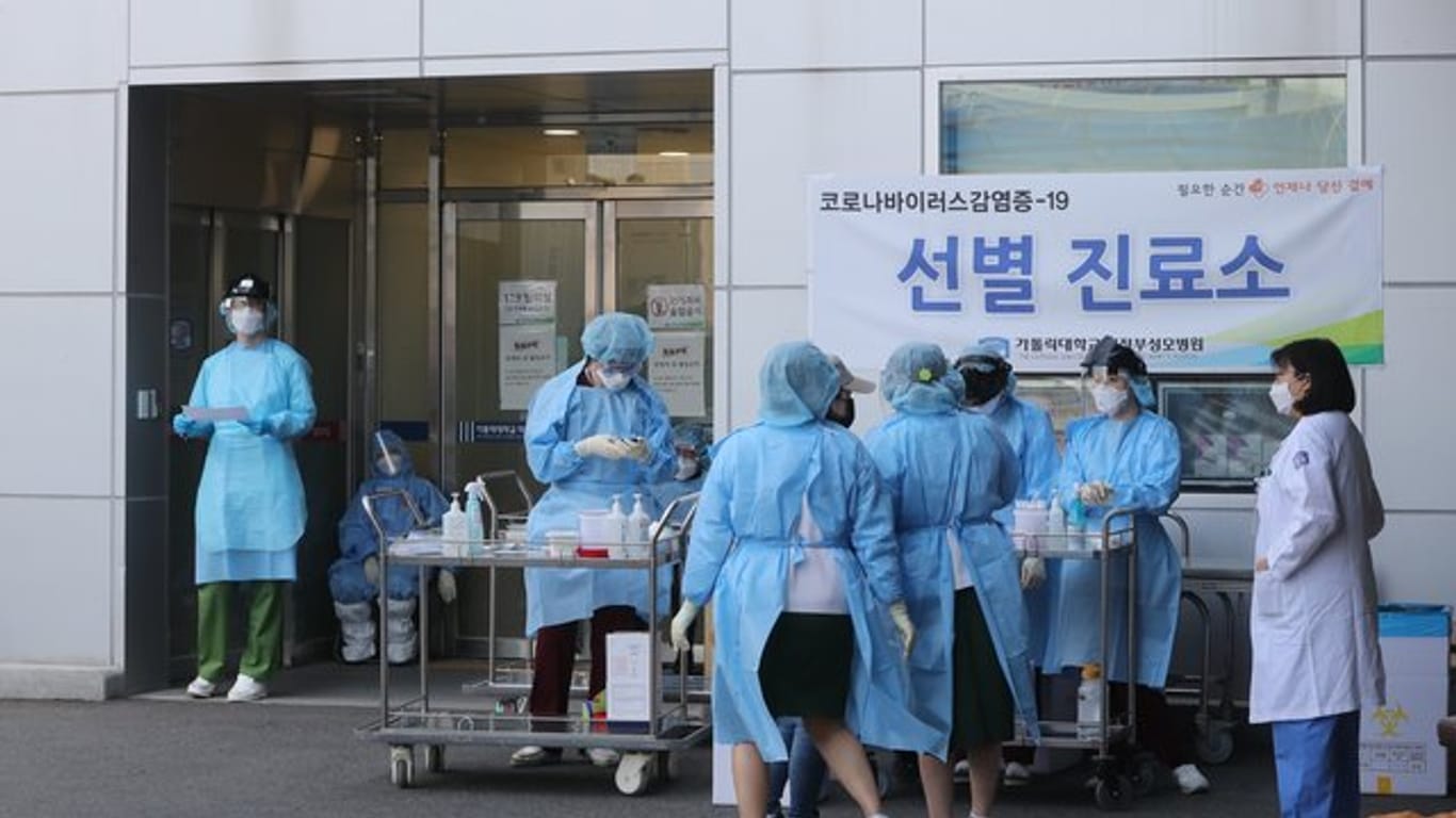 Medizinisches Personal in Schutzausrüstung steht vor einem Krankenhaus in Südkorea.