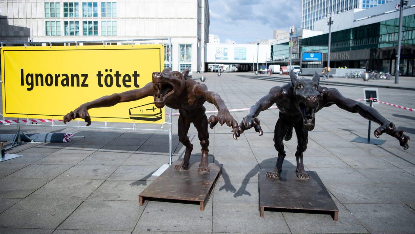 Zwei Wölfe stehen am Alexanderplatz, auf einem Transparent steht "Ignoranz tötet": Aktionskünstler Opolka hat die Bronzefiguren aufgestellt.