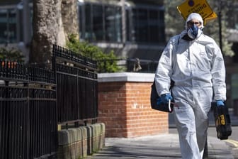 Ein Mann geht im Schutzanzug über eine Straße in Westminster im Zentrum Londons.