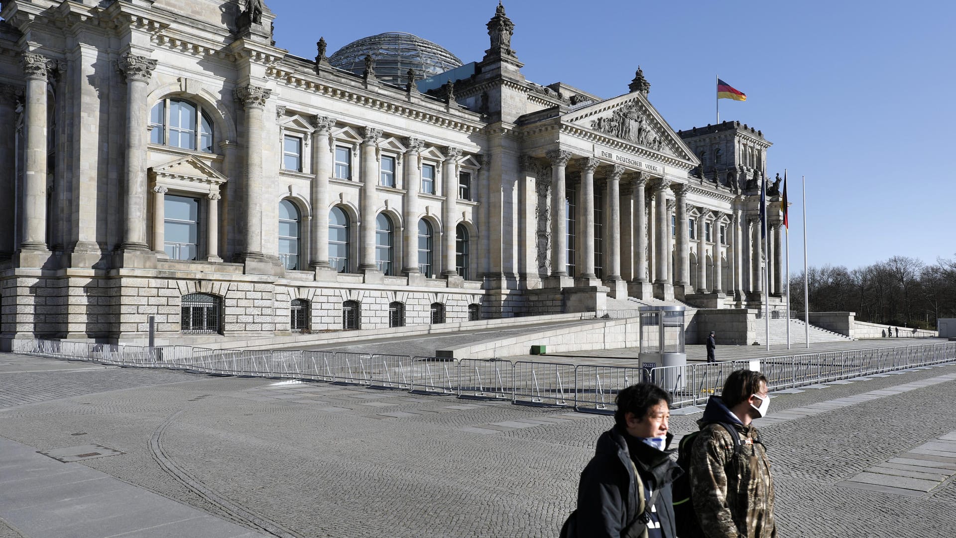 Menschen mit Schutzmasken am Reichstagsgebäude in Berlin: Vorerst kommt keine Pflicht zum Tragen solcher Masken.